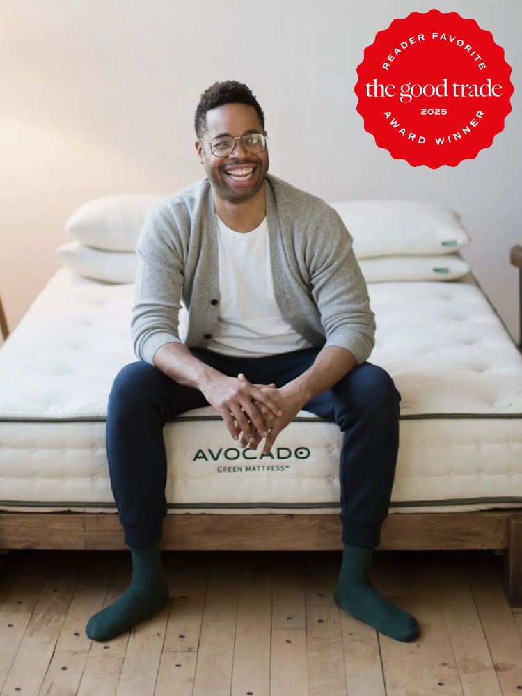 Person sitting on a bed with "Avocado Green Mattress" text, wearing casual clothing. A red badge on the image reads "Reader Favorite, the good trade, 2025, Award Winner.