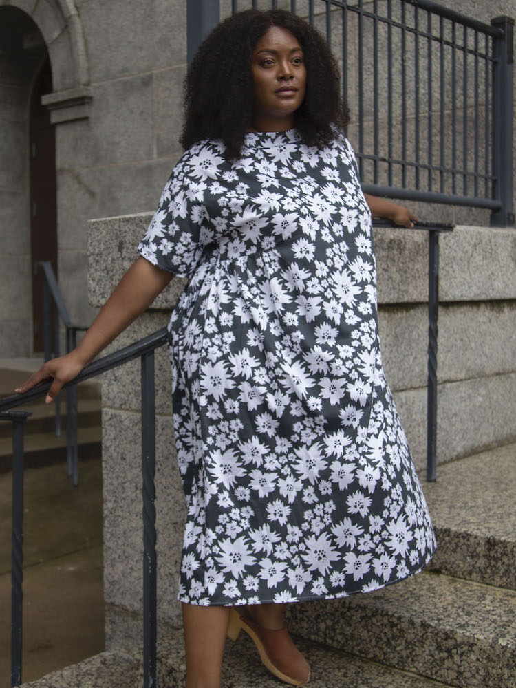 A model wearing a black and white floral midi dress from Hackwith Design House. 