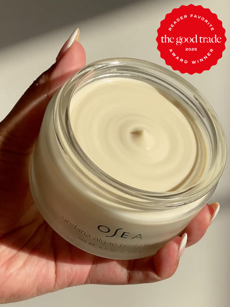 Hand holding a jar of OSEA undaria algae body butter with a smooth, creamy texture. A red badge indicates it is a 2025 award winner from The Good Trade.