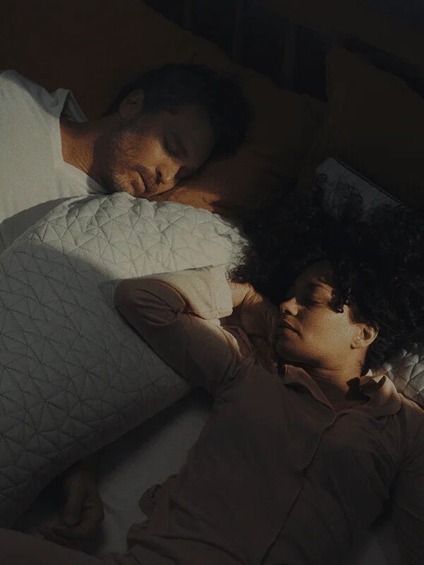 A couple sleeping with a Coop pillow between them.