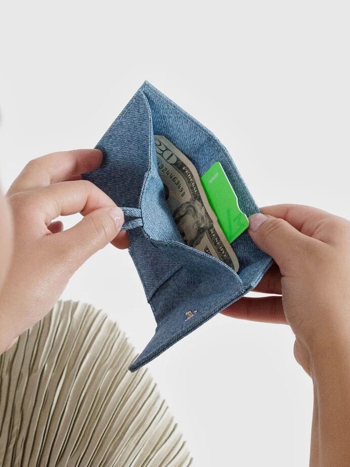 A close up of a model opening the inside of a BAGGU wallet.