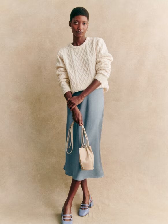 A model wearing an Ice Blue silk skirt from Sezane.