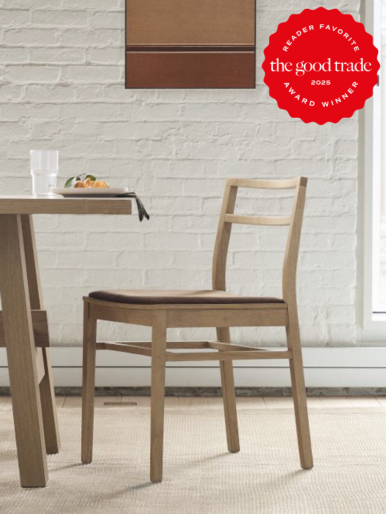 Wooden chair beside a table with a dish and glass, against a white brick wall. "The Good Trade 2025 Reader Favorite Award Winner" logo in the top right corner.