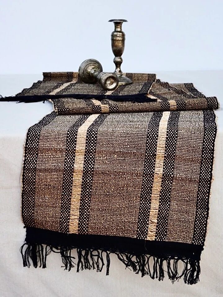 A woven black, brown, and yellow striped table runner from Terraklay.
