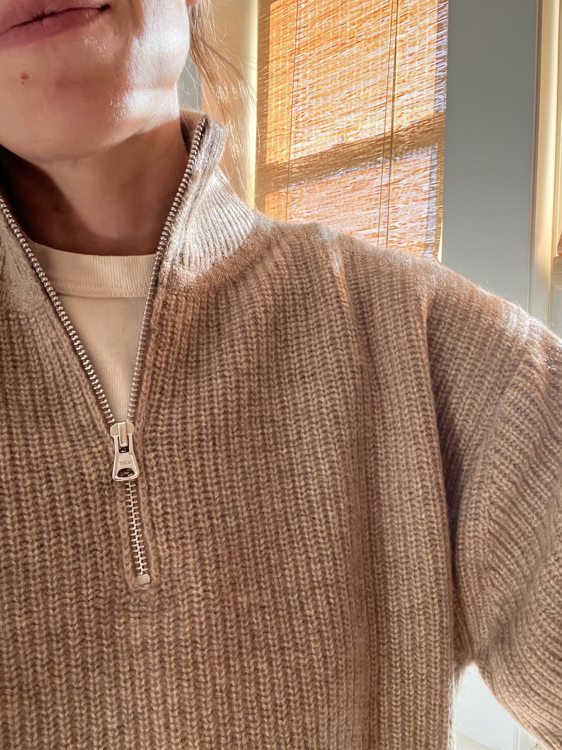 A closeup selfie of a half-zip oatmeal colored sweater on a woman whose chin and mouth are partially visible.