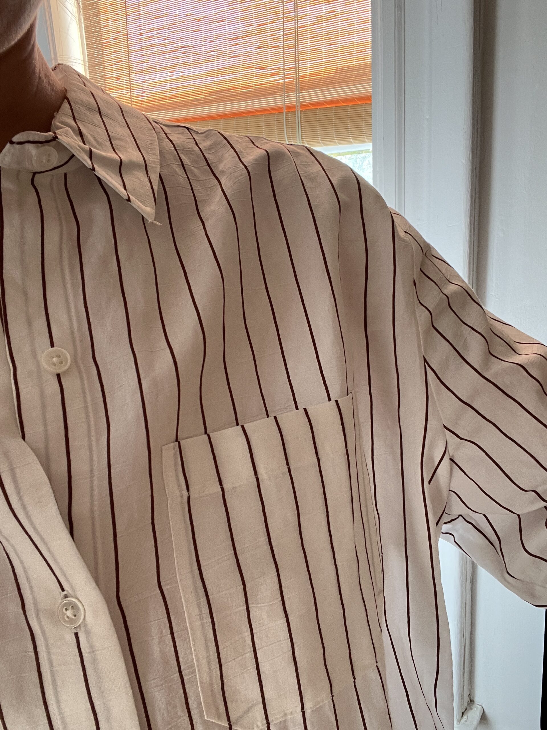 A close up selfie of a woman's shoulder and the top of a striped button down. 