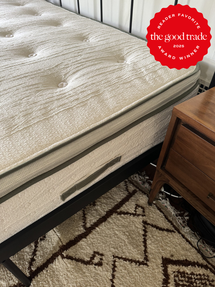 A neatly made bed with a white mattress, a patterned rug underneath, and a wooden nightstand beside it. A red badge on the image reads, "Reader Favorite, The Good Trade, 2025 Award Winner.