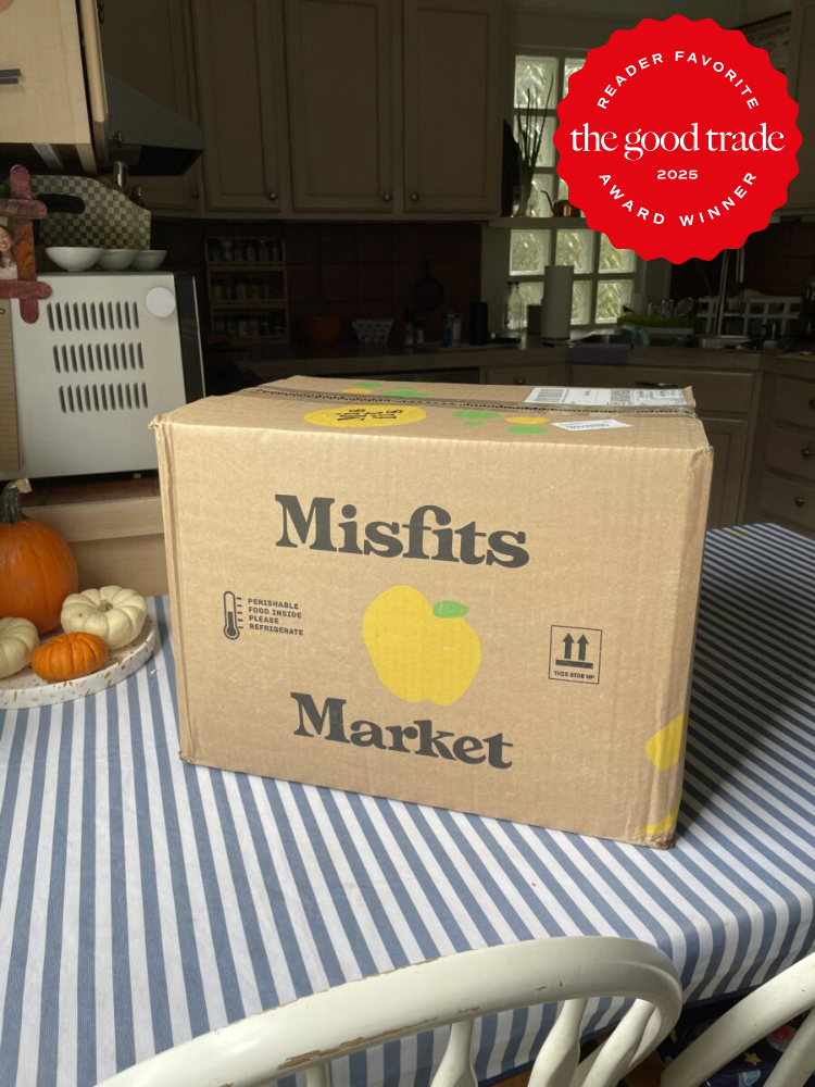 Cardboard box labeled "Misfits Market" on a striped tablecloth, with small pumpkins nearby. Award badge for "The Good Trade" 2023 in the image corner.
