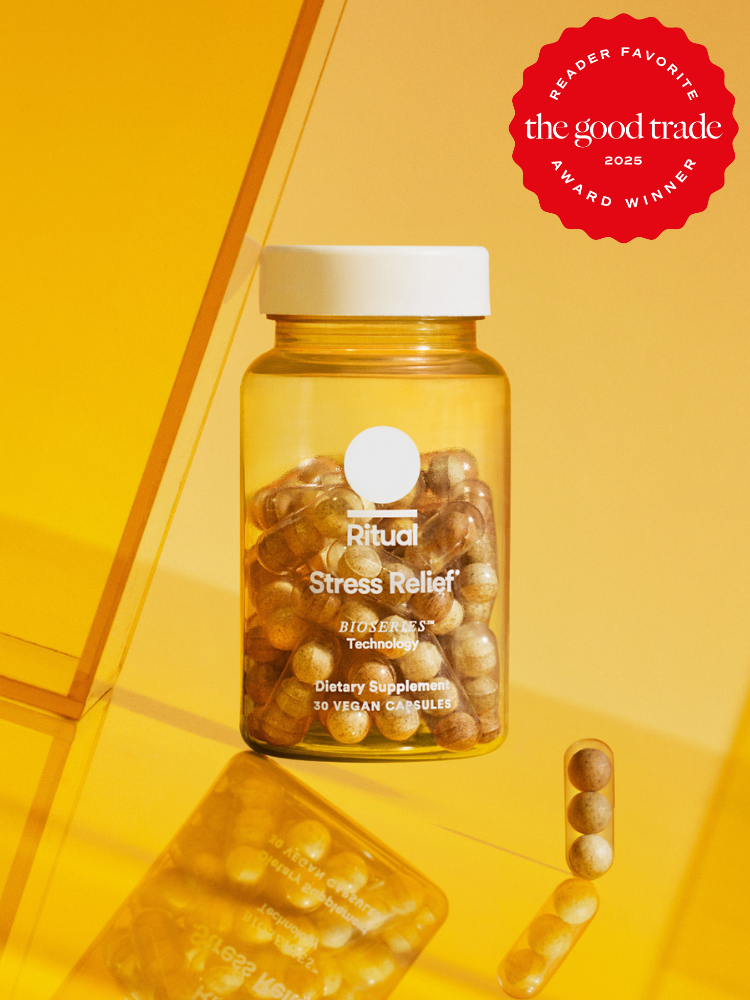 A bottle of Ritual Stress Relief vegan capsules on a yellow background, labeled as a reader favorite award winner by The Good Trade in 2025.