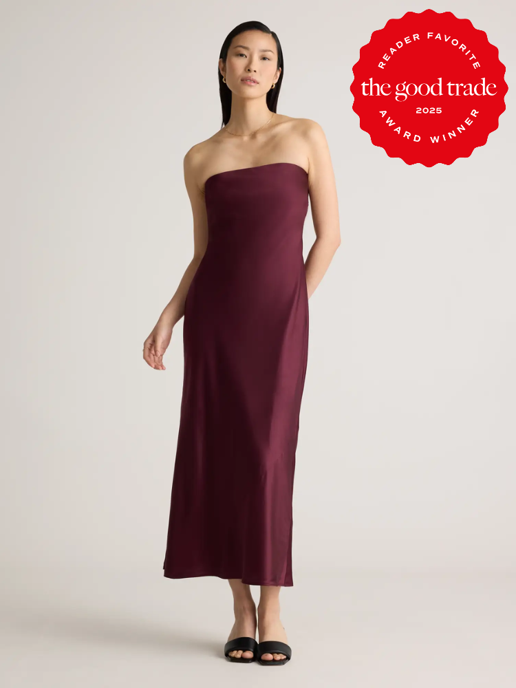 Woman in a strapless burgundy dress and black sandals stands against a plain background. Red badge in corner reads "Reader Favorite, the good trade, Award Winner 2023.