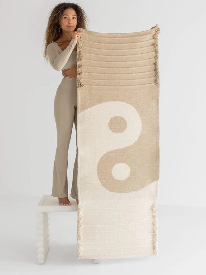 A model holding up an Oko Living yoga mat. 