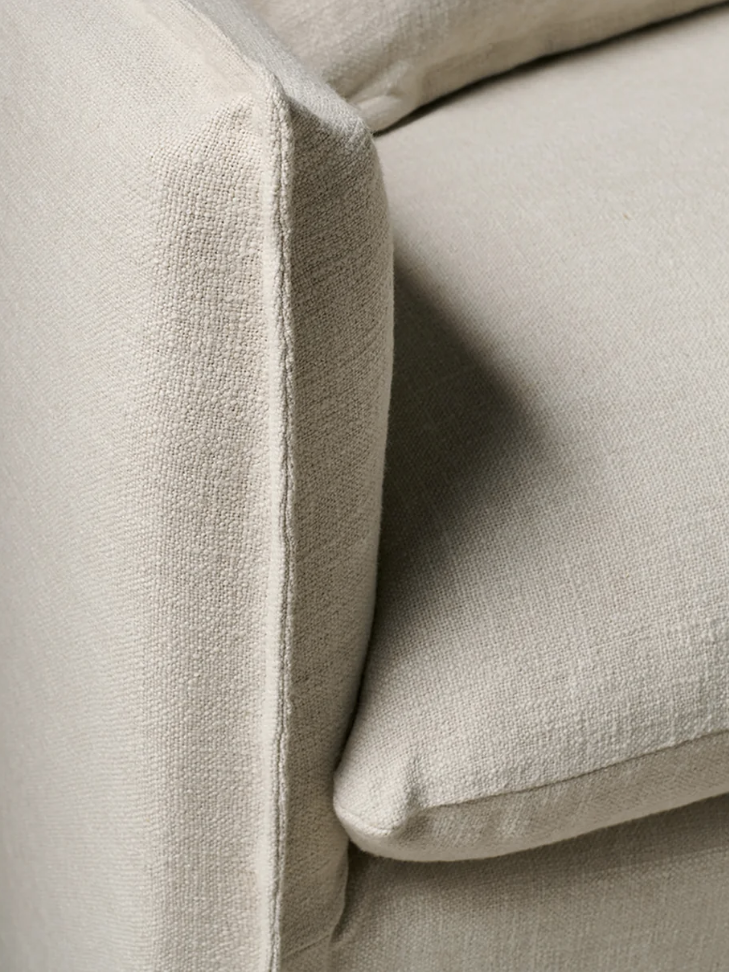 Close-up of a light beige fabric sofa corner, showing the cushion and armrest details.