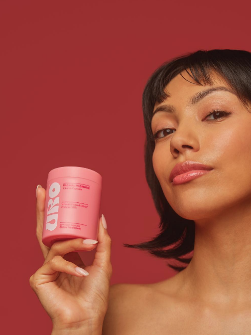 Person holding a pink URO container against a red background.