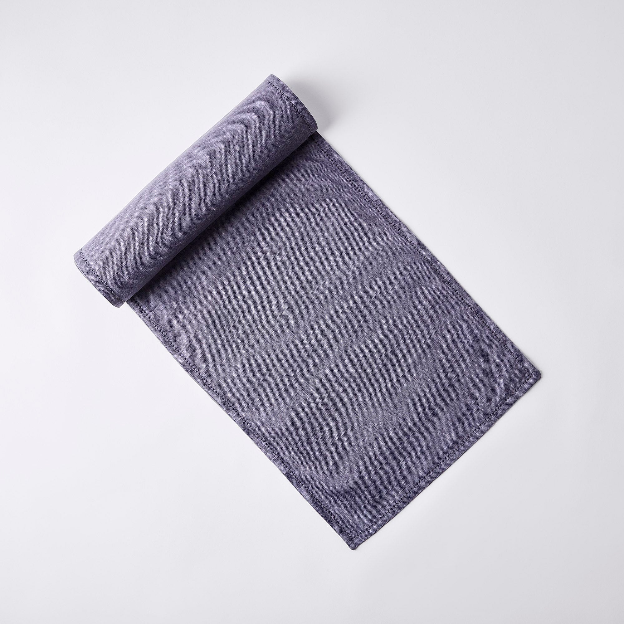A rolled-out, rectangular, purple cloth napkin set on a plain white background.
