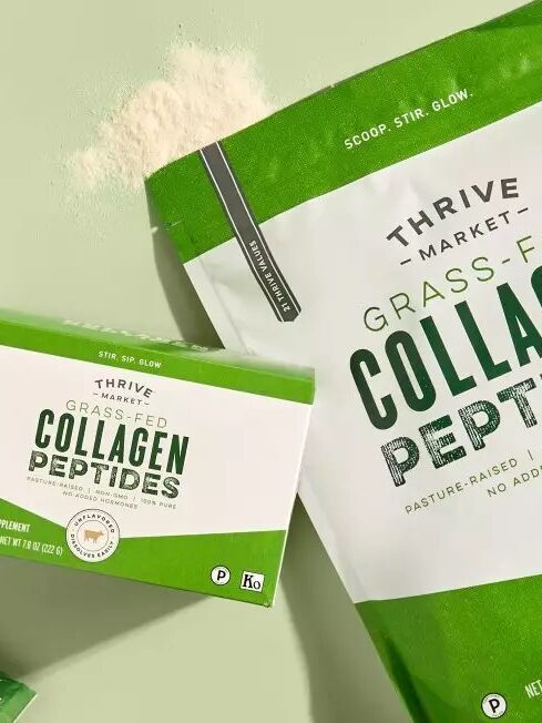 Packaging of Thrive Market grass-fed collagen peptides, including a large bag, a box, and single-serving packets on a green surface with a small pile of powder.