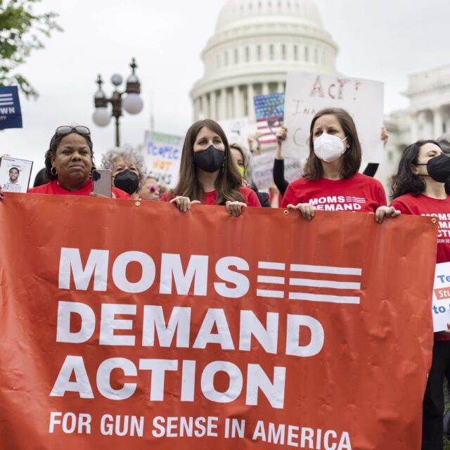 A group of women wearing red shirts hold a "Moms Demand Action for Gun Sense in America" banner during a protest in front of the U.S. Capitol building.