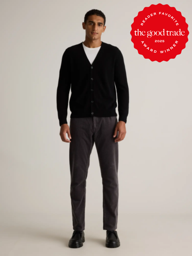 A person stands facing forward, wearing a black cardigan, white shirt, gray pants, and black shoes. A red "The Good Trade 2025 Reader Favorite Award Winner" badge is visible in the top right.