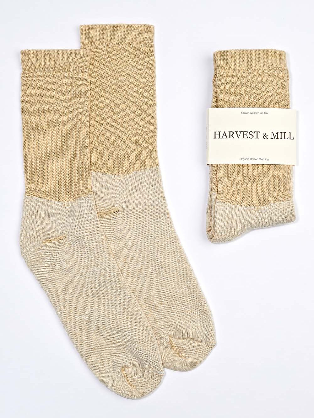 Two pairs of beige organic socks, one folded with a "Harvest & Mill" label, placed on a white background.
