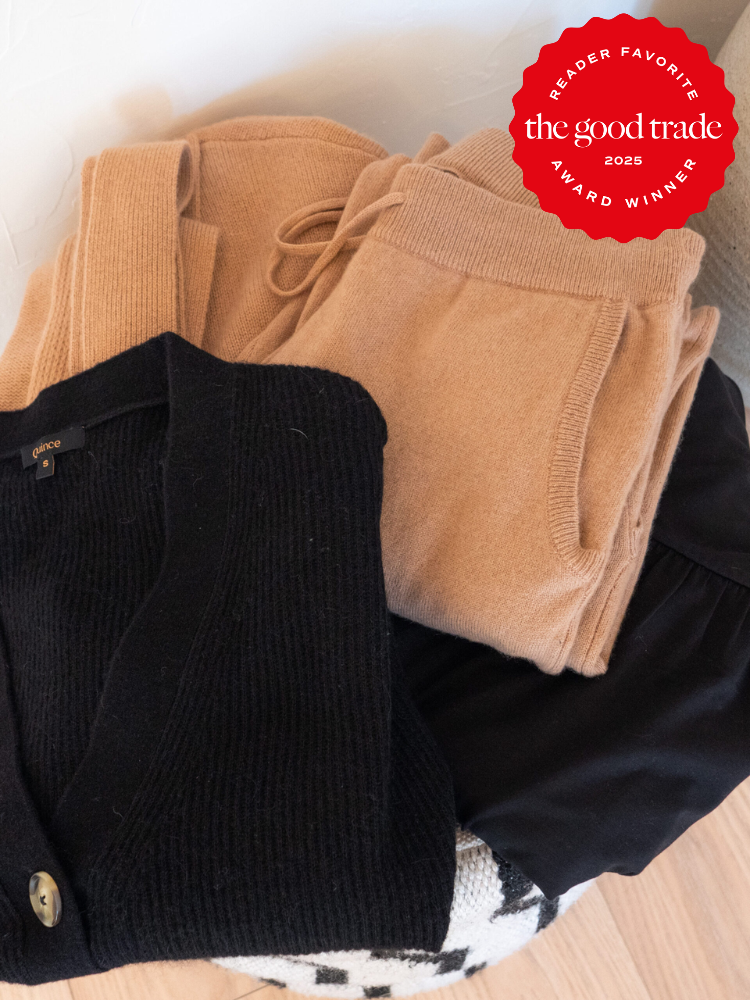 Folded black and beige clothing, including a black cardigan and beige pants, with an award-winning label from "The Good Trade" indicating reader favorite for 2025.