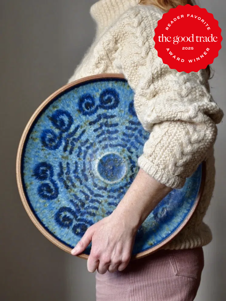 Person holding a large circular blue ceramic plate with spiral patterns, wearing a knitted sweater. "Reader Favorite Award Winner 2025" badge in the top right corner.