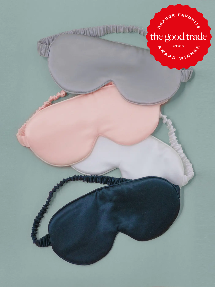 Four eye masks in gray, pink, white, and black are stacked on a green background. A red "Reader Favorite" award badge from "The Good Trade 2025" is displayed in the top right corner.