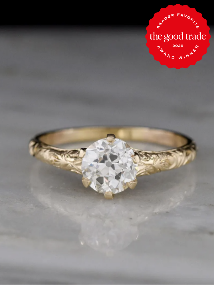 Gold ring with an ornate band featuring a round diamond. A red badge in the corner reads "Reader Favorite, the good trade, 2025, Award Winner.