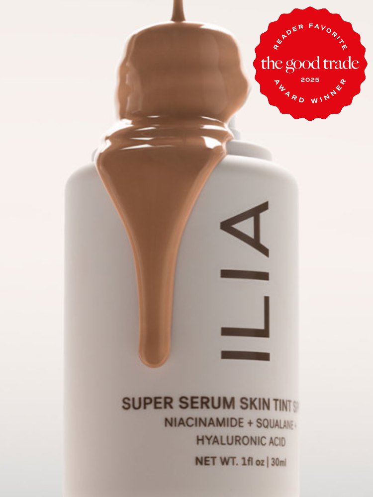A bottle of ILIA Super Serum Skin Tint with brown liquid spilled over the cap. A red "Reader Favorite" award sticker is on the upper right corner.