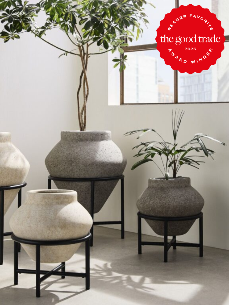 Four large stone pots with plants on black metal stands in a bright room. The top right has a red badge labeled "Reader Favorite, the good trade, 2025 Award Winner.
