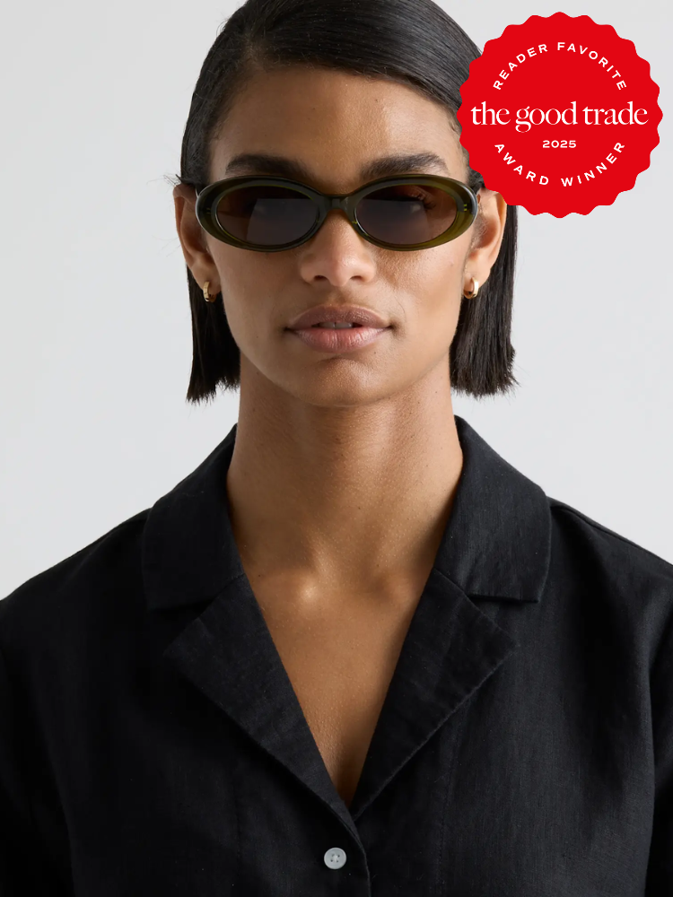 Person wearing oval sunglasses and a black shirt, with a red award badge from "The Good Trade" at the top right corner.
