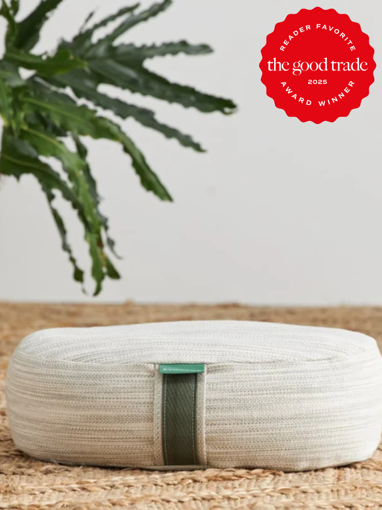 Round, textured white cushion on woven mat with a green tag, next to a leafy plant. Red seal in corner reads, "The Good Trade 2025 Reader Favorite Award Winner.