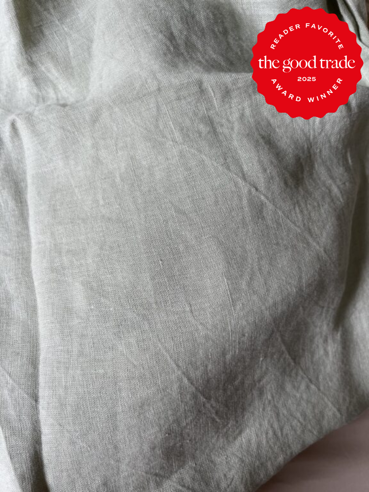 Close-up of crumpled, light gray fabric with a red circular badge in the top right corner, stating "Reader Favorite The Good Trade Award Winner 2025.