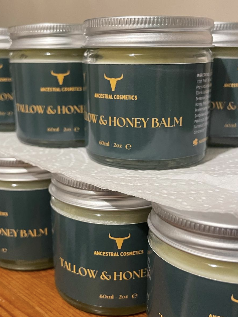 Jars of Tallow & Honey Balm by Ancestral Cosmetics are stacked on a surface. Each jar contains 60ml or 2oz of balm.