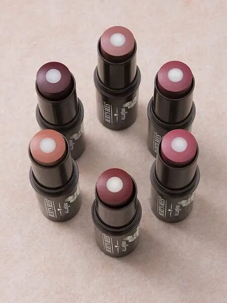 Six tubes of lipstick, each with a different shade, arranged in a circular pattern on a neutral background.