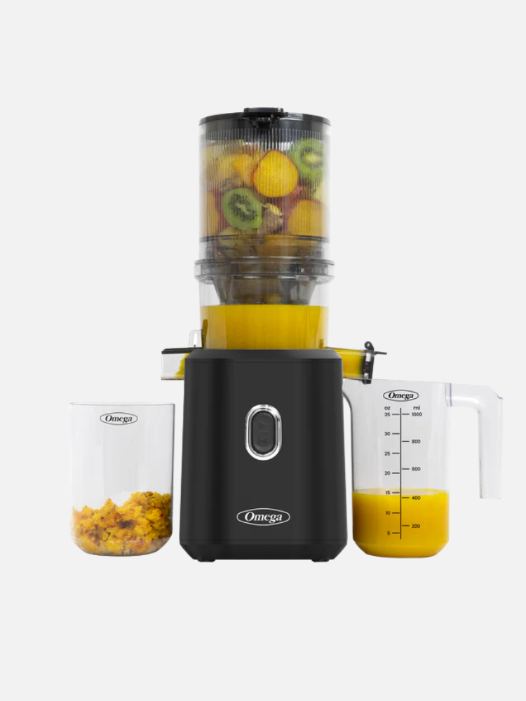 A black juicer with pulp and juice containers, filled with chopped fruits, including kiwis, in a transparent chamber.