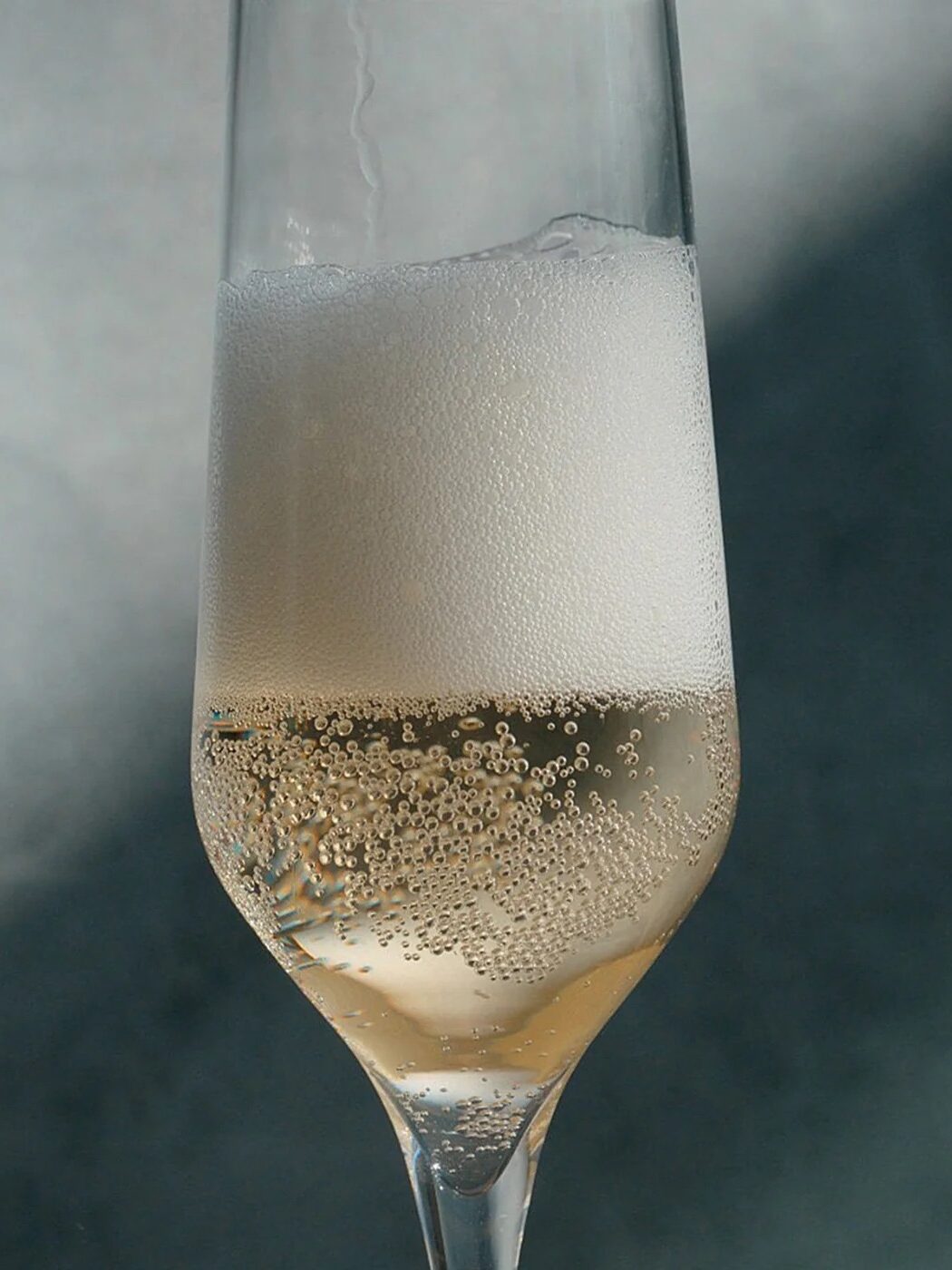 A champagne flute filled with bubbling champagne against a blurred background.