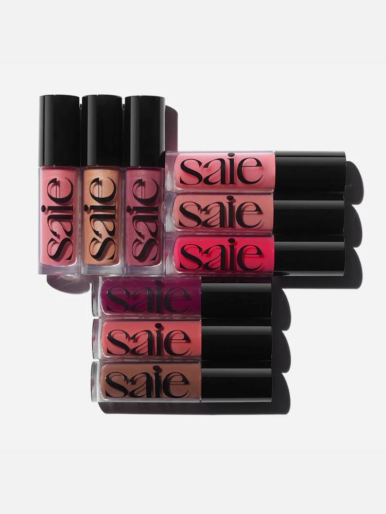Collection of six lip glosses in various shades, labeled with "saie" branding, arranged in two rows against a white background.