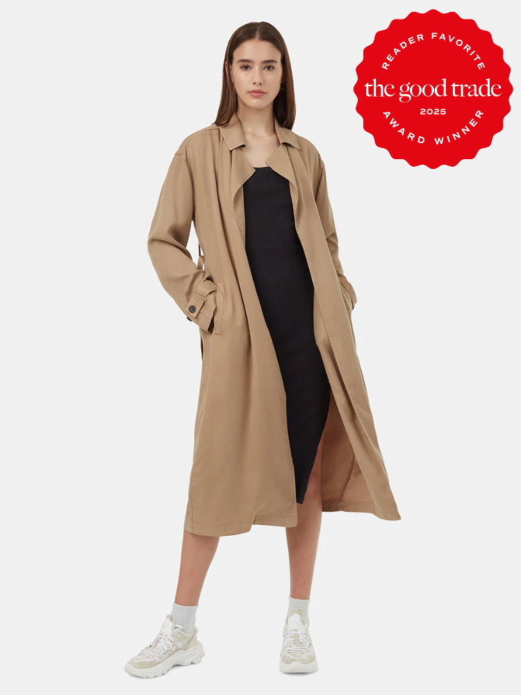 Woman in a black dress and beige trench coat poses in sneakers. Red badge reads "Reader Favorite, the good trade, Award Winner 2023.