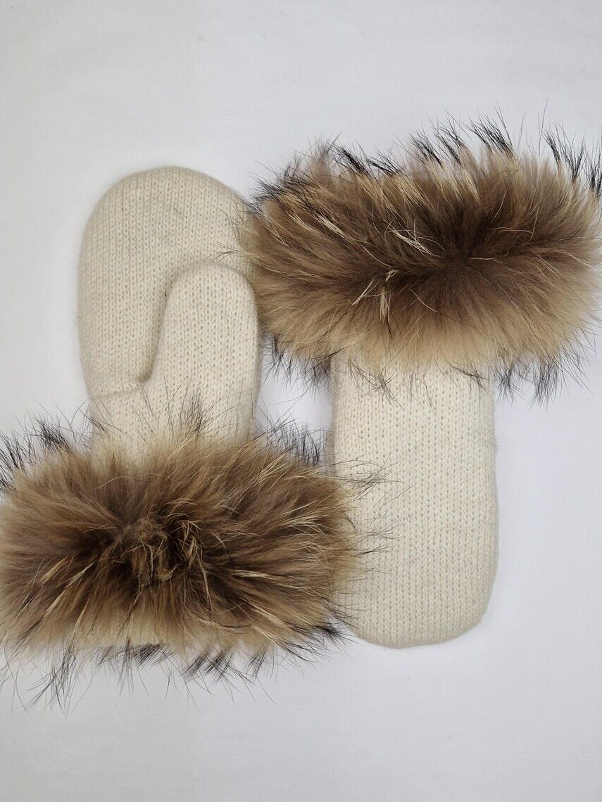A pair of cream-colored knit mittens with brown fur trim around the wrists, placed on a white background.