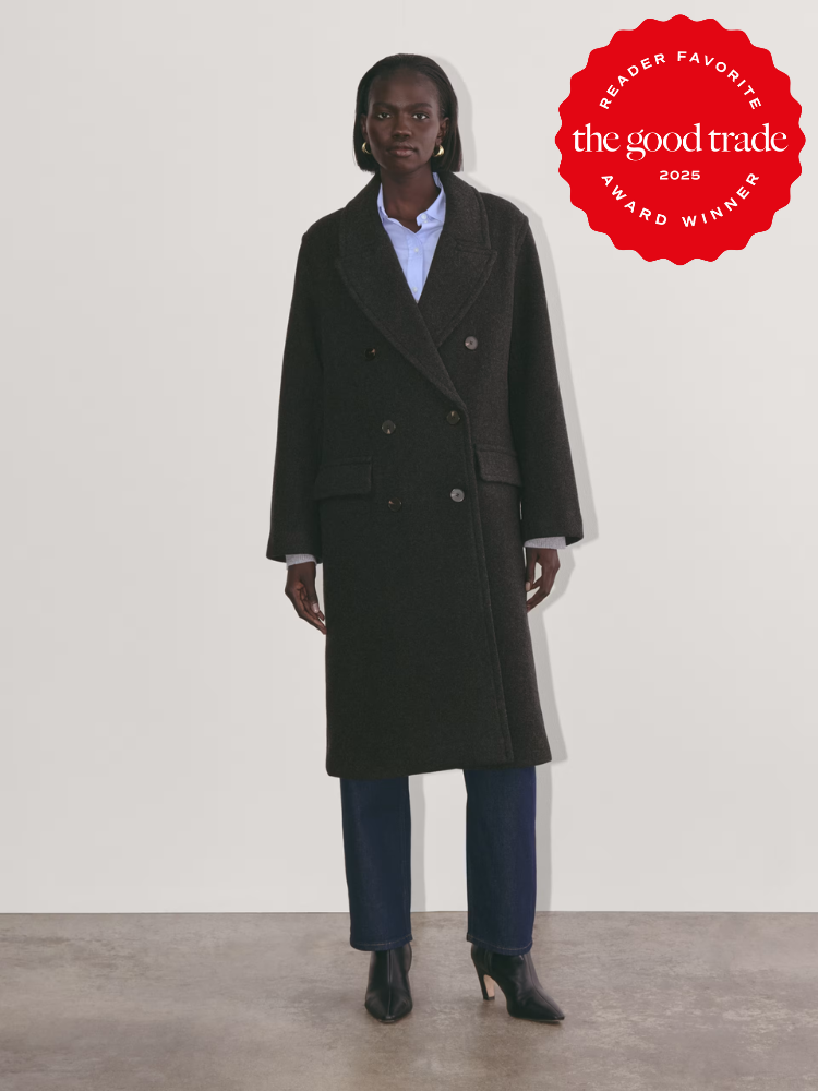 Person wearing a dark wool coat over a blue shirt and jeans with black heeled boots. "The Good Trade 2025 Reader Favorite Award Winner" badge is on the top right.
