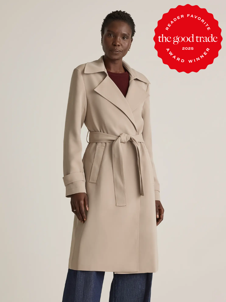 Person wearing a beige trench coat with a tie belt, standing against a plain backdrop. There's a "The Good Trade 2023 Reader Favorite Award Winner" badge in the top right corner.