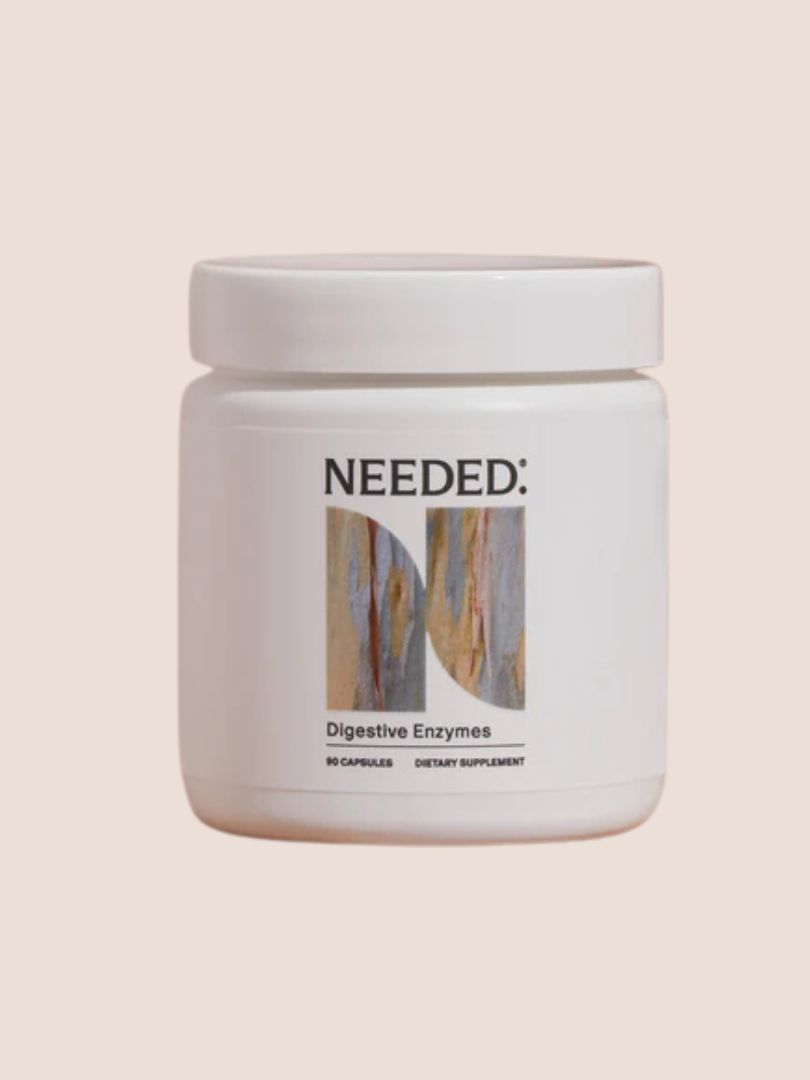 A white jar labeled "NEEDED: Digestive Enzymes" containing 90 capsules of dietary supplement against a light pink background.