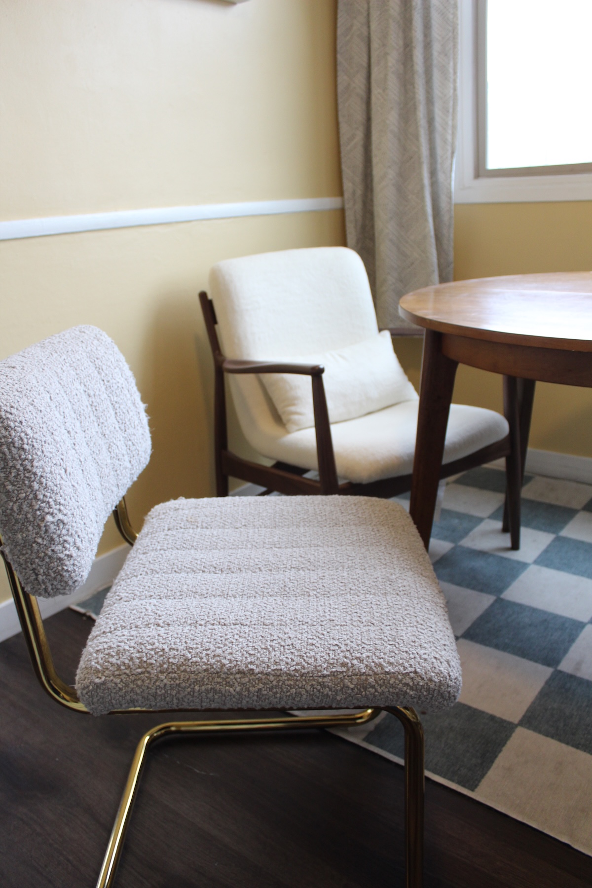Two chairs and a wooden table in a room with yellow walls and a window.