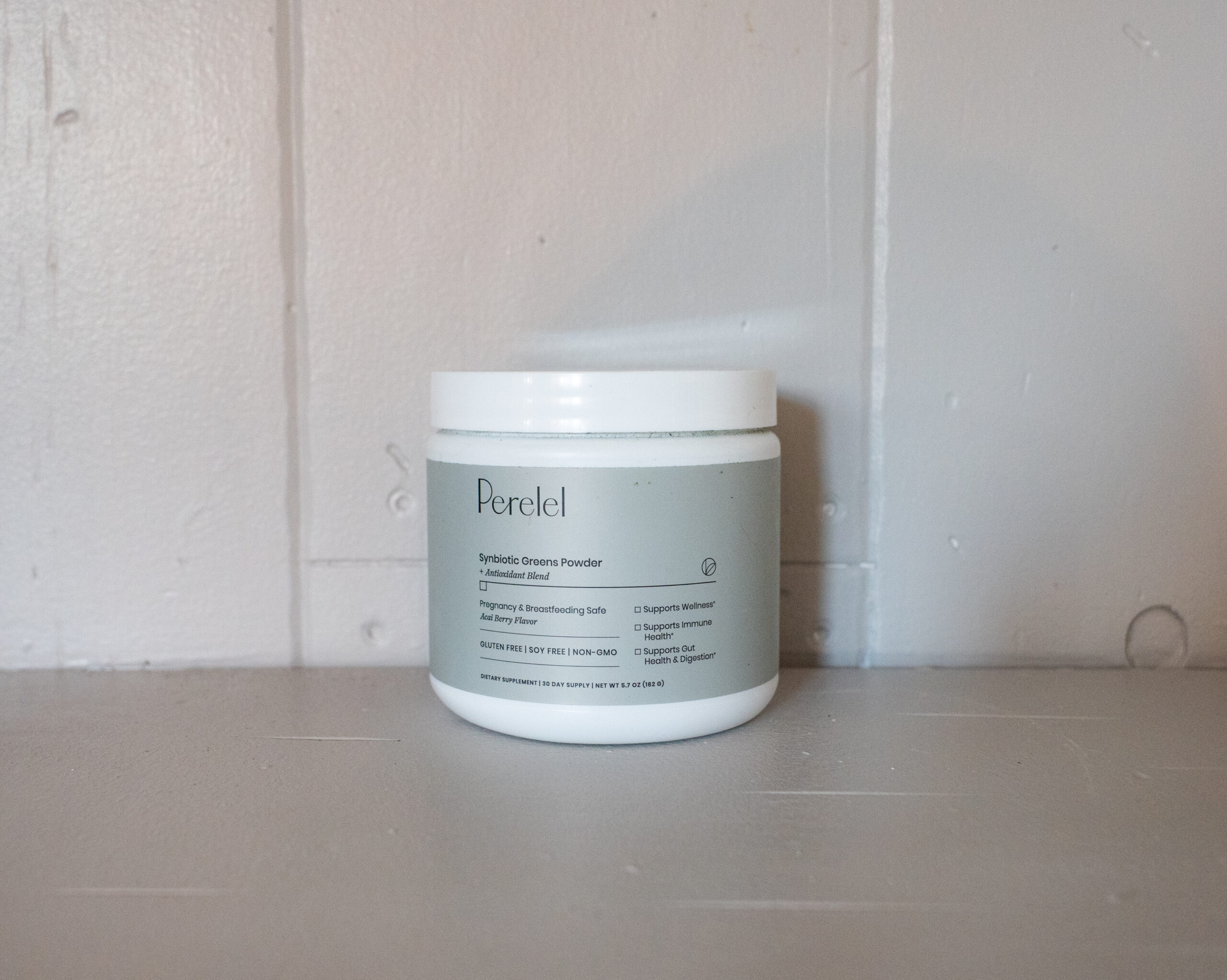 A jar labeled "Perelel" stands on a wooden surface against a light-colored wall.