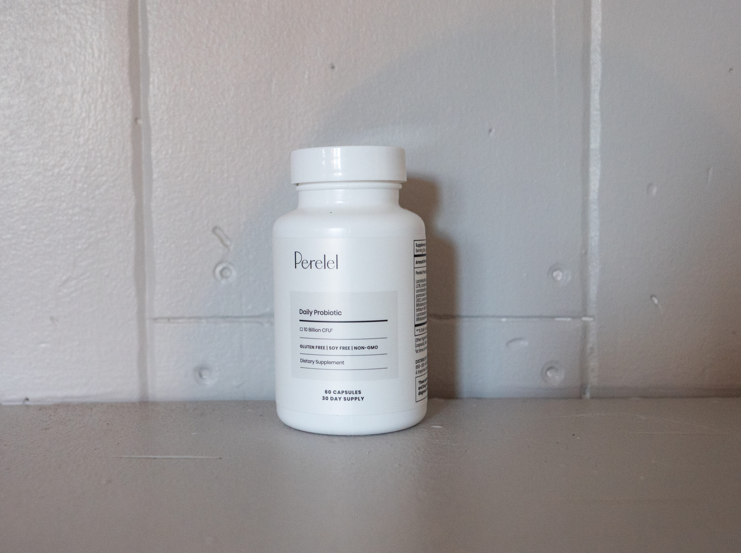 A white bottle labeled "Daily Probiotic" sits on a gray surface against a light gray wall.