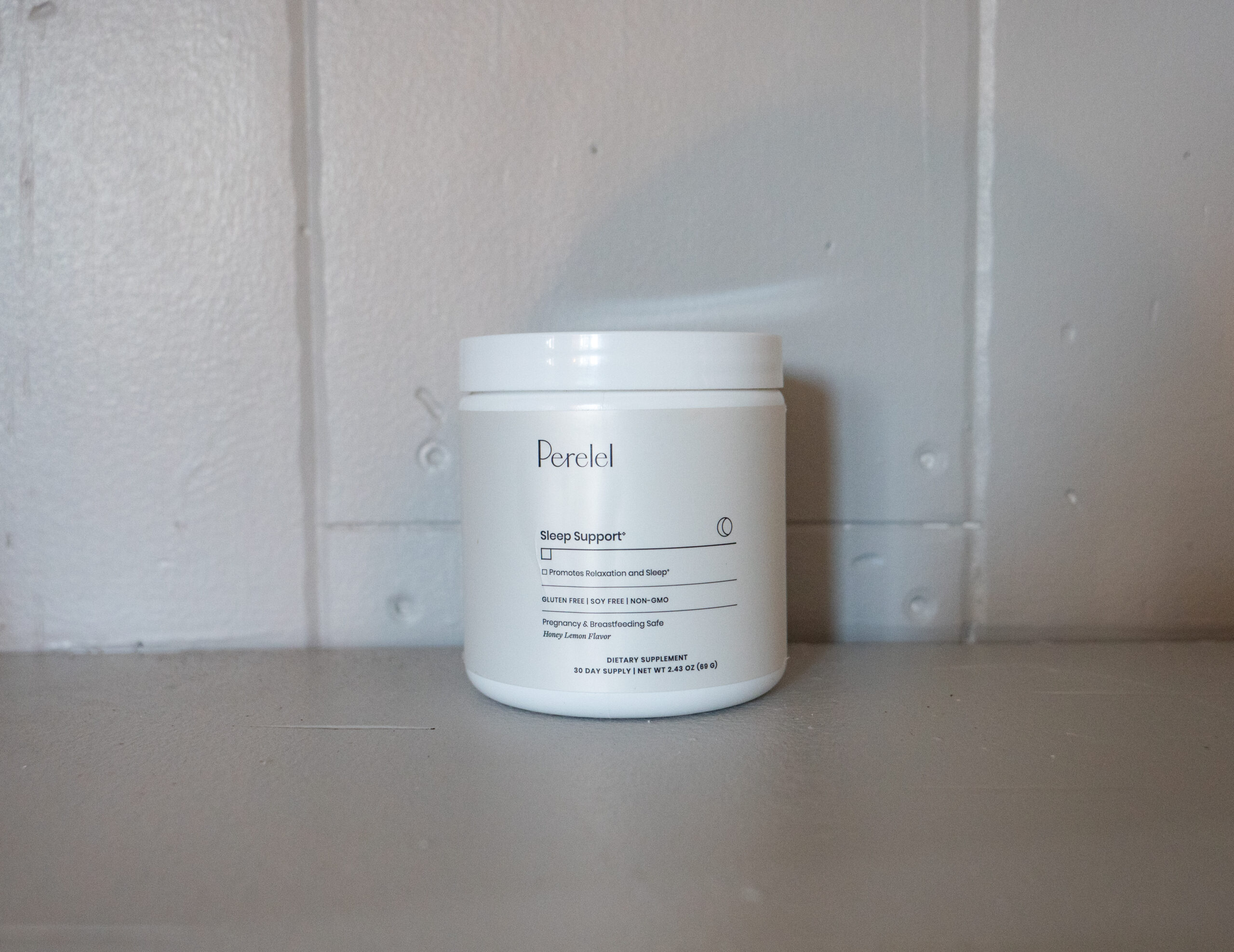 White jar labeled "Perelel Sleep Support" against a light gray wall, sitting on a ledge.