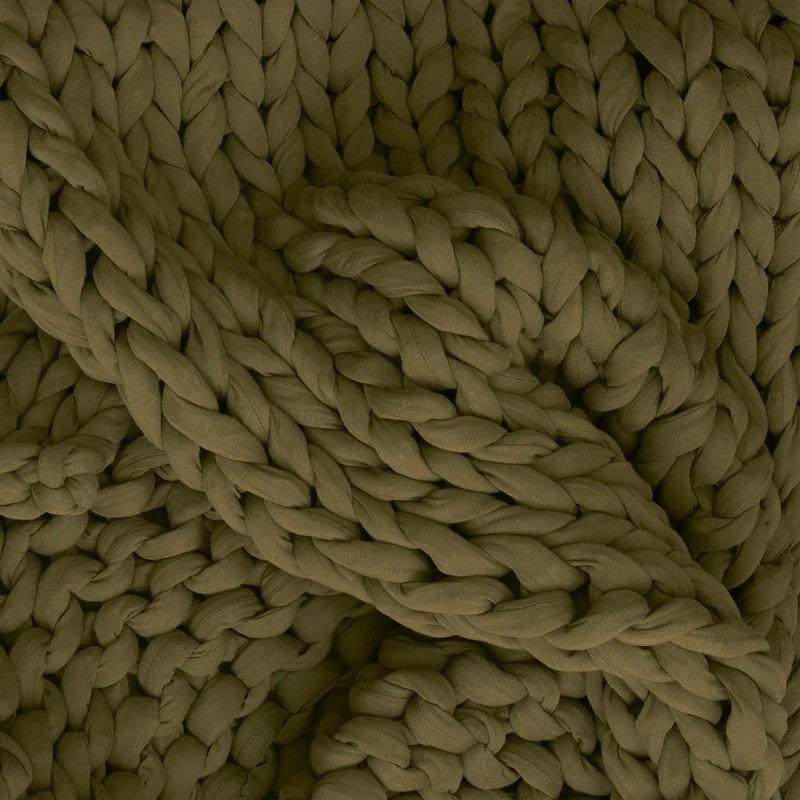 Close-up of a chunky knit fabric in olive green, showing thick, interwoven yarn strands in a braided pattern.