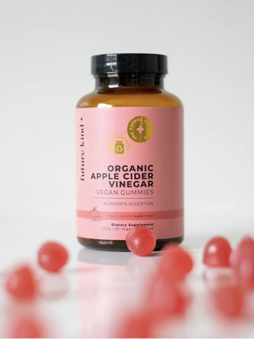 A bottle of organic apple cider vinegar vegan gummies is displayed against a light background, surrounded by scattered red gummies.