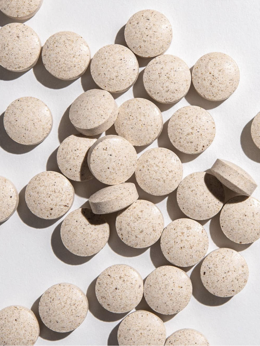 Round beige tablets scattered on a white surface.