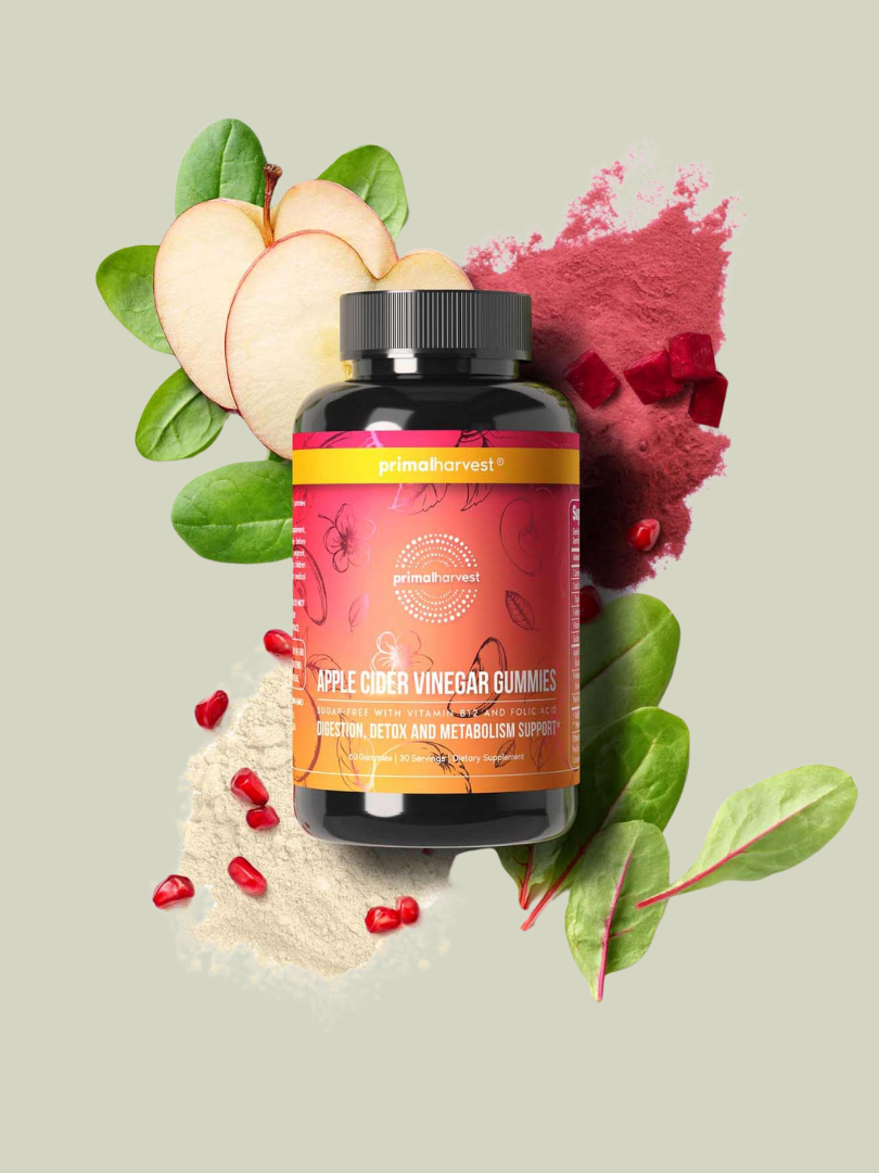 A bottle of apple cider vinegar gummies surrounded by apple slices, beetroot powder, spinach leaves, and pomegranate seeds on a light background.