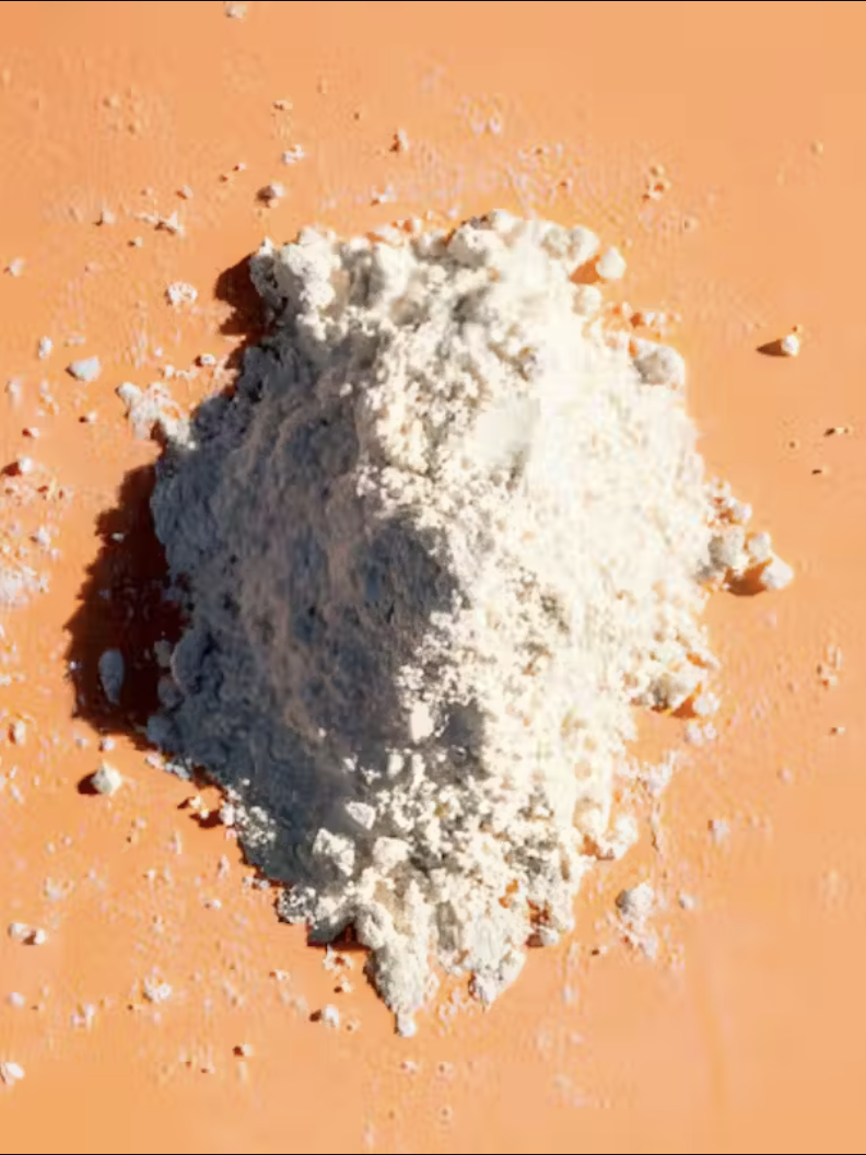A pile of white powder on a smooth, light orange surface.